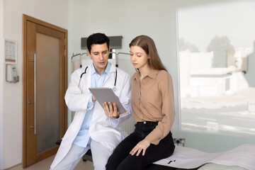 Serious young Hispanic physician man explaining medical report, diagnosis, electronic exam results...