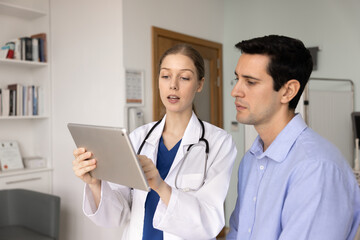 Serious young medical specialist woman explaining checkup report, diagnosis, test results on...