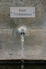 „Kein Trinkwasser“-Schild über sprudelndem Rohr mit Wasserfluss