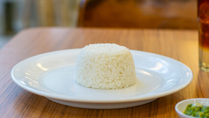 A plate of neatly shaped white rice on a wooden table, ready to be served.