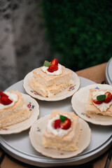 Mini cakes with cream and strawberries on plates