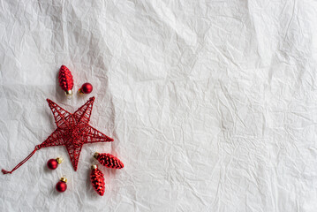 Red Christmas decorations on paper texture background, red star, and pinecones.