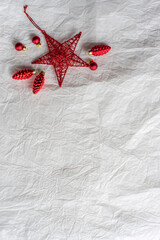 Red Christmas decorations on paper texture background, red star, and pinecones.
