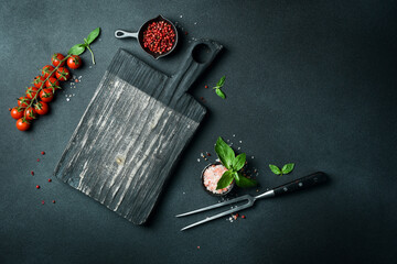 Cooking background, free space for text. Kitchen cutting board, spices and herbs. On a black stone...