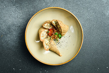 Liver pancakes with mushrooms and cheese. On a plate. Restaurant serving. Close up. On a dark stone background.