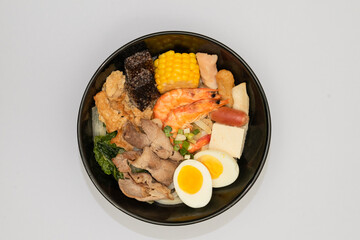 A hearty bowl of seafood noodle soup filled with shrimp, corn, egg, vegetables, rice blood cake, tofu skin, and assorted hotpot ingredients. The colorful ingredients float in a rich broth, making for 