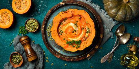 Homemade pumpkin cream soup with pumpkin seeds and cream prepared in a pumpkin. Dietary nutrition. Top view.