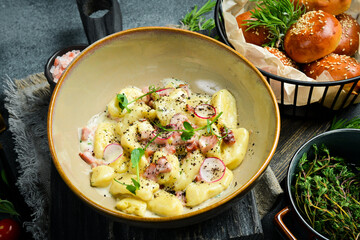 Potato gnocchi with bacon and sour cream. On a black stone background. Bread.