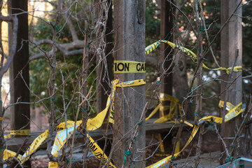 yellow caution tape tied around a wooden pole with branches