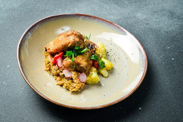 Stewed pork ribs in a cream sauce, with boiled potatoes. On a plate. Restaurant serving. Close up. On a dark stone background.