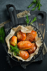 Freshly baked buns with sesame in a basket. On a black stone background. Bread.