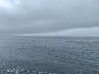 Grey overcast sea with gentle waves and a cloudy sky, tranquil atmosphere, minimalist seascape with...