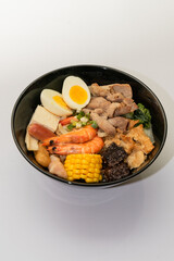 A hearty bowl of seafood noodle soup filled with shrimp, corn, egg, vegetables, rice blood cake,...