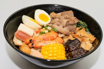 A hearty bowl of seafood noodle soup filled with shrimp, corn, egg, vegetables, rice blood cake, tofu skin, and assorted hotpot ingredients. The colorful ingredients float in a rich broth, making for 