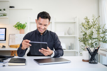 Confident businessman using digital tablet while smiling at his modern office desk.