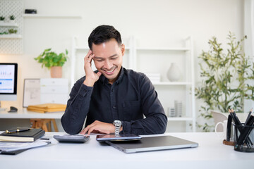 Smiling businessman working on digital tablet at modern desk in bright home office.