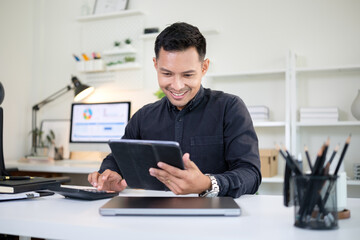 Confident businessman using digital tablet while smiling at his modern office desk.