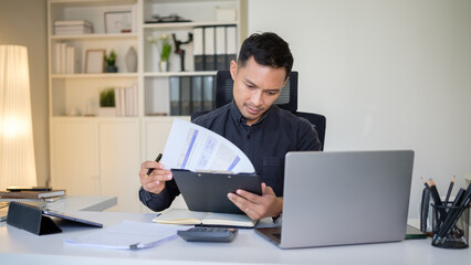 Focused businessman analyzing financial documents at his desk in a modern office.