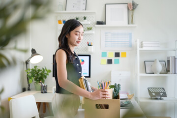 Sad businesswoman packing personal belongings in a box after losing her job.