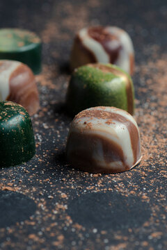 Delicious artisanal chocolates displayed on a textured surface with cocoa powder and intricate designs