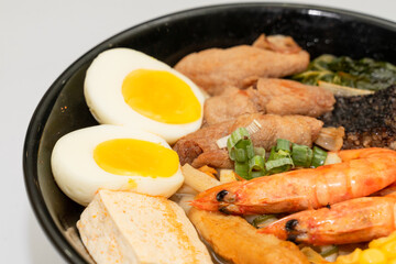 A hearty bowl of seafood noodle soup filled with shrimp, corn, egg, vegetables, rice blood cake, tofu skin, and assorted hotpot ingredients. The colorful ingredients float in a rich broth, making for 