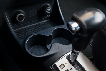Interior view with  two cupholders and armrest of black used car stands in the showroom after dry washing before sale