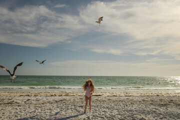 Tween girl feeding seagulls on beach Anna Maria Island