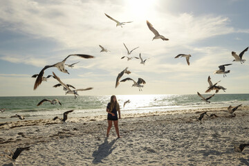 Teenage girl feeding seagulls on beach Anna Maria Island