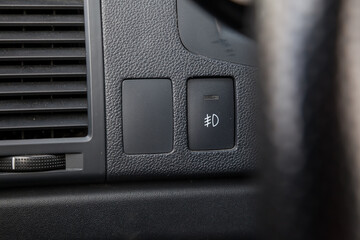 Close-up on the headlight switch control buttons and automatic adjust level dashboard of car in the...