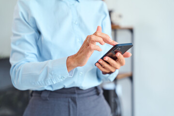 Professional Showing a Businessperson’s Hands Using a Mobile Phone, Displaying Communication, Technology, and Professionalism in a Modern Office Setting