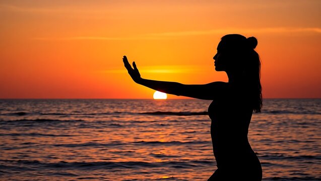 Silhouette of a woman practicing tai chi on a beach during a vibrant orange sunset over the ocean
