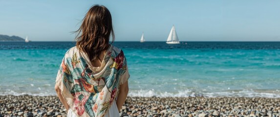 Woman in Floral Shawl Gazing at Sailboats on a Sunny Beach Peaceful Scene.