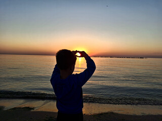 A child and the sun rising over the Black Sea. In Mamaia, Constanta