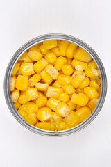 An overhead close-up shot perfectly captures an open can filled to the brim with vibrant, golden corn kernels, presented on a minimalist white background