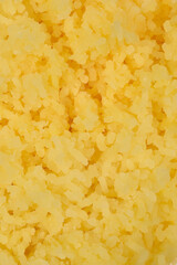 A close-up, full-frame shot captures the textured appearance of a heap of light yellow, finely...