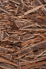 A textured close-up features a generous pile of irregular dark chocolate shavings, perfect for culinary applications or as a delightful topping