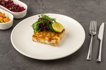 Spanish tortilla with potato and chicken, topped with fresh greens and lime