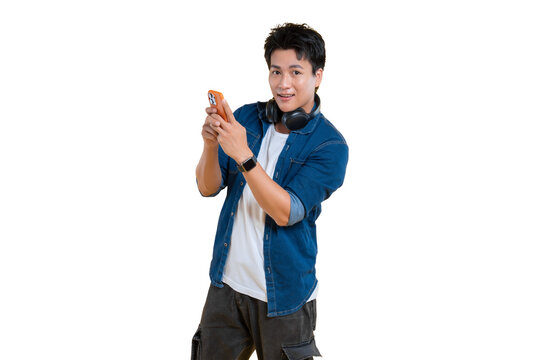 Young man holding a mobile phone, possibly taking photo or using app while headphones around his neck. Dressed casually with a light smile, and smartwatch on png background