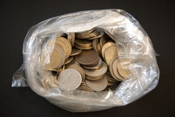 Open transparent plastic bag with Hungarian forint coins spilling out. Shot on black background
