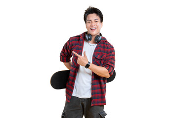 A young man holding a skateboard, pointing at something with a smile on his face. He is wearing a...
