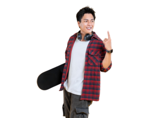 A young man holding a skateboard with headphones around his neck, pointing his index finger up and smiling on png background