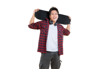 A cheerful young man holding a skateboard over his shoulders. He's wearing a stylish outfit, and his headphones are around his neck.on png background