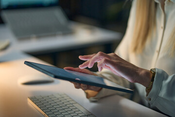 Close-Up Of A Woman Using A Digital Tablet On A Desk, Demonstrating Modern Technology And Connectivity, Set In A Low-Light Professional Office Environment For Business And Productivity Themes