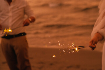 a sparkler sparkling at the beach during sunset