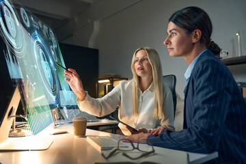 Two Businesswomen Collaborating on a Futuristic Digital Project in a Modern Office Setting....