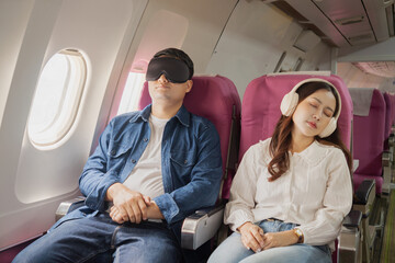Asian couple sleeping together on a passenger plane