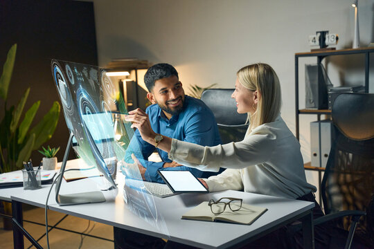 Two Colleagues Collaborating In Modern Office, Analyzing Interactive Holographic Screen Displays At Night, Focusing On Innovative Technology And High-Tech Solutions