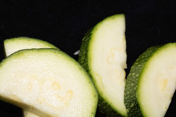 Close up of cut chopped home grown courgette zucchini on black background