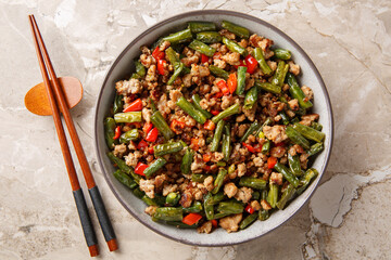 Crispy Pork Stir Fry with Green Beans, garlic and bell pepper closeup in the bowl on the table. Horizontal top view from above