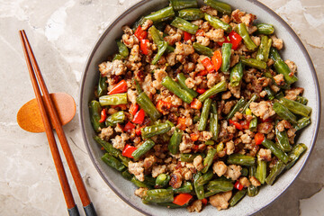 Asian food stir-fried green bean with minced pork closeup in the bowl on the table. Horizontal top view from above